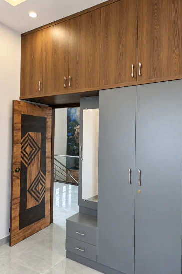 Bedroom wardrobe design at the completed Krishnamurthy residence in Makali, Bangalore, with grey cabinets, a dressing mirror and wood-finish loft storage.