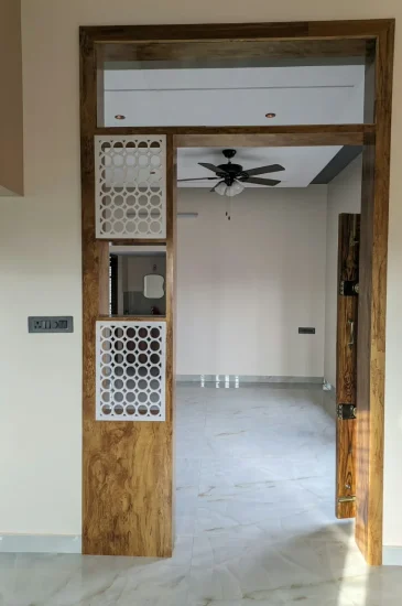 Home entrance interior design at the Krishnamurthy residence in Makali, Bangalore, with a wood-finish frame and decorative lattice panels.