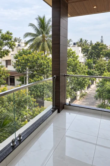 Balcony design in Bangalore at the Krishnamurthy residence in Makali, with a glass railing, tiled floor and views of greenery.