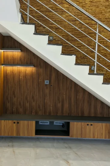 Under staircase interior design at the completed Krishnamurthy residence in Makali, Bangalore, with wood-finish cabinets and illuminated display shelves.