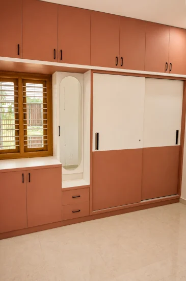 Completed bedroom wardrobe design in Bengaluru for the Laxman project, with full-height cabinets, overhead storage and a dressing niche beside the window.