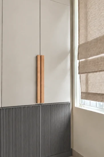 Bedroom wardrobe design at the completed Palaksha Residency in Bagalgunte, Bangalore, with white upper cabinets, dark fluted lower panels and wooden handles