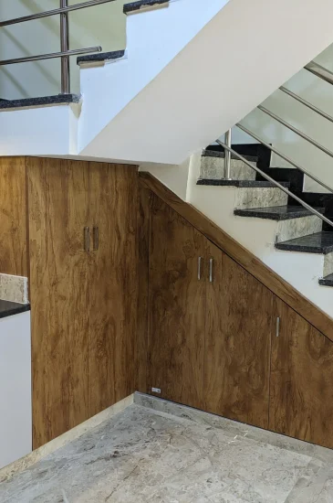 Under staircase storage design at the completed Palaksha Residency in Bagalgunte, Bangalore, with wood-finish cabinetry beside the kitchen